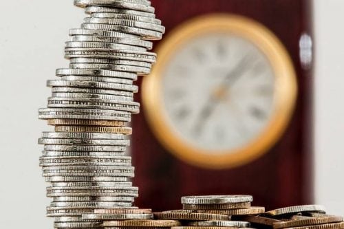 coins stacked high clock in background