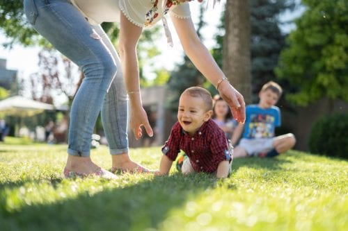 Mother reaches down to pick up her small child at the park