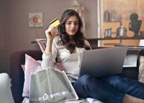 Young woman holds credit card as she shops online