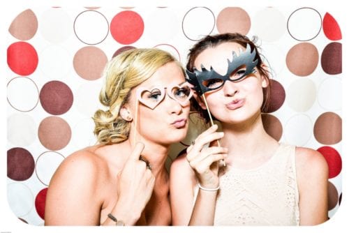 Two women pose for a picture wearing masquerade eye wear