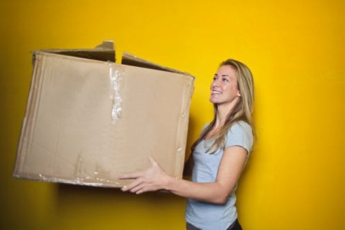 Young woman carrying a big brown box