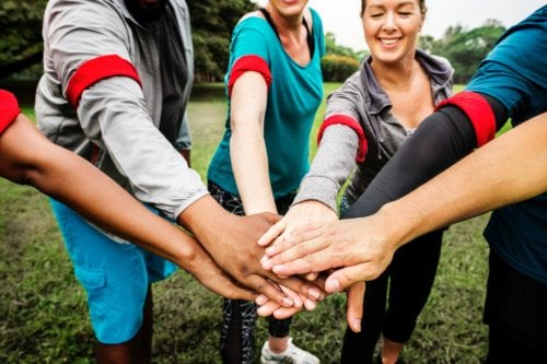A group puts their hands together in an all in salute