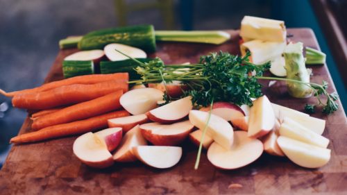 Food cut up on table, including apples and carrots