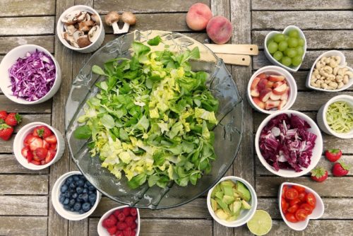 Salad surrounded by add-ins and raw ingredients