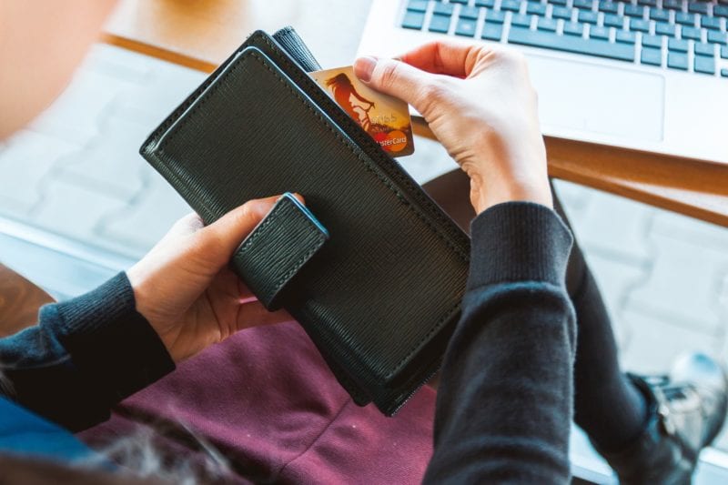 Person pulling a credit card out of a black wallet