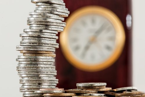 Coins stacked up in front of a clock