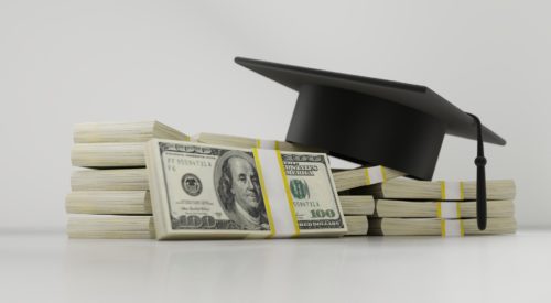 A graduation cap on top of stacks of money