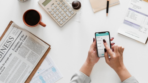 a person holding a phone over a desk 