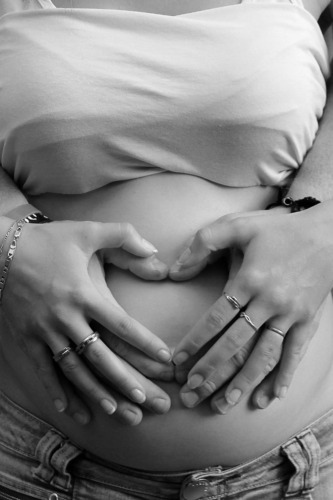 woman making a heart over a pregnant belly