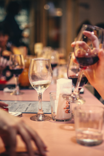 A table full of wine glasses with people discussing an airbnb vs hostel